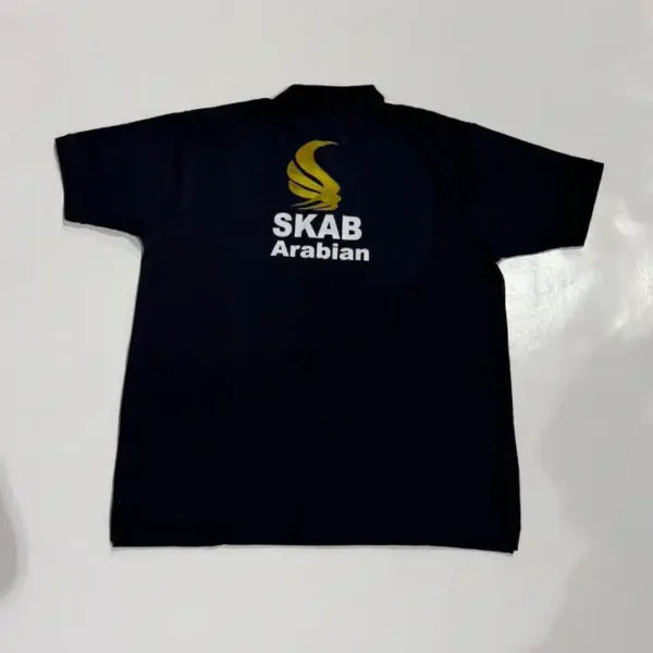 تيشيرت بولو أسود مفرود من الجهة الخلفيه يحمل طباعة رقمية دقيقة وبارزة لشعار شركة SKAB Arabian باللونين الذهبي والأبيض باحترافية على الصدر